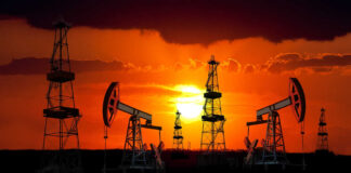 Silhouetted oil rigs against a vibrant sunset