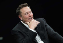 Elon Revives GOP Turnout Machine Man in suit smiling, resting chin on hand.