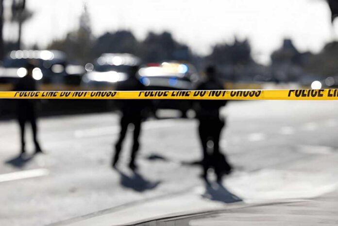 2758684351 Police tape cordons off a street with blurred officers and vehicles in the background