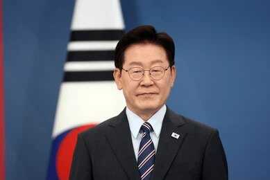 2796180043 Man in suit with glasses standing before South Korean flag