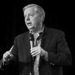 Man in a suit speaking into a handheld microphone