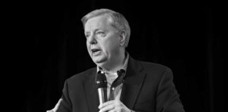 Man in a suit speaking into a handheld microphone