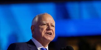 A government official delivering a speech at a podium with a blue background