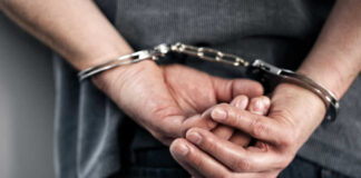 Hands cuffed behind the back, indicating arrest