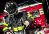 Manhattan High-Rise Faces Collapse Risk Firefighter adjusting gear in front of a fire truck