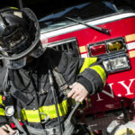 Manhattan High-Rise Faces Collapse Risk Firefighter adjusting gear in front of a fire truck