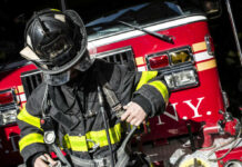 Firefighter adjusting gear in front of a fire truck