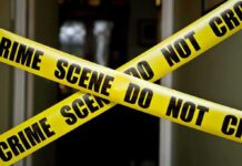 Probe Widens After Epstein Ally Found Dead Yellow crime scene tape crossing a doorway