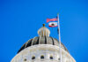California Law Fuels New Controversy View of a state capitol dome with American and California flags against a blue sky