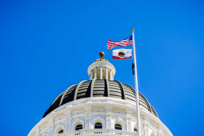 April,14,,2018,Sacramento,/,Ca,/,Usa,-,The View of a state capitol dome with American and California flags against a blue sky