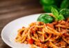 Pasta Promo Outranks Elections? Spaghetti bolognese topped with basil on a white plate