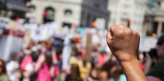 Raised fist in foreground at a crowded street protest