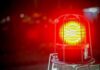 Red emergency warning light with protective cage glowing at night