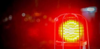 Red emergency warning light with protective cage glowing at night