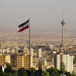 Iran Strike Campaign Shows No Pause Iranian flag over Tehran skyline with Milad Tower