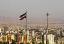 Iran Strike Campaign Shows No Pause Iranian flag over Tehran skyline with Milad Tower
