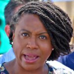 Body Found Sparks Political Firestorm woman speaking at outdoor event