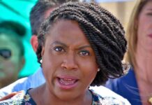 Body Found Sparks Political Firestorm woman speaking at outdoor event