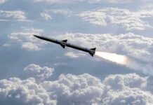 Rocket flying above clouds with bright exhaust plume
