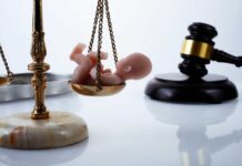 Officer Convicted In Unborn Child Killing Scales of justice with a baby figurine and a gavel in the background