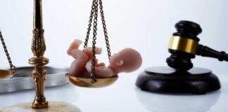 Scales of justice with a baby figurine and a gavel in the background