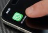 WhatsApp Halted — Fraud Panic Or Power Play? Finger tapping the WhatsApp icon on a smartphone screen