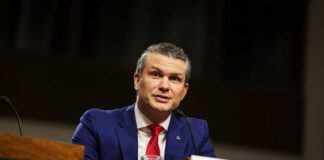 Man in a blue suit speaking at a government hearing
