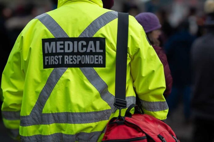 Close,Up,Of,A,Medical,First,Responder,Wearing,A,Bright Medical first responder wearing a bright yellow jacket and carrying a red bag