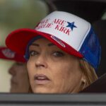 Erika Kirk Faces Accused Killer A woman wearing a cap with a political message, looking out from a vehicle