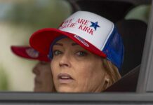 Erika Kirk Faces Accused Killer A woman wearing a cap with a political message, looking out from a vehicle