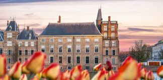 Panoramic view of a historic government building with Danish flags and bicycles in the foreground