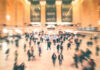 A busy train station filled with blurred figures of people moving