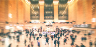 A busy train station filled with blurred figures of people moving