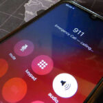 Cyberattack Cripples City Lifeline Phone screen showing 911 emergency call in progress.