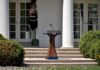 DA Vows To Blow Up Trump’s Ballroom Podium with presidential seal in a garden colonnade