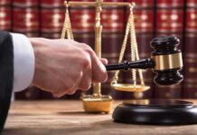 Judge's hand holding gavel near scales of justice
