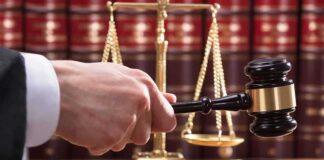 Judge's hand holding gavel near scales of justice