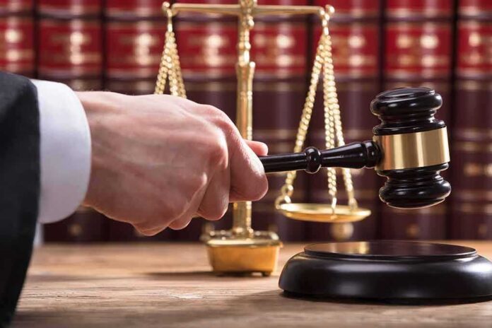 shutterstock_1073806559 Judge's hand holding gavel near scales of justice