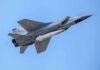 fighter jet with missile flying against a clear blue sky