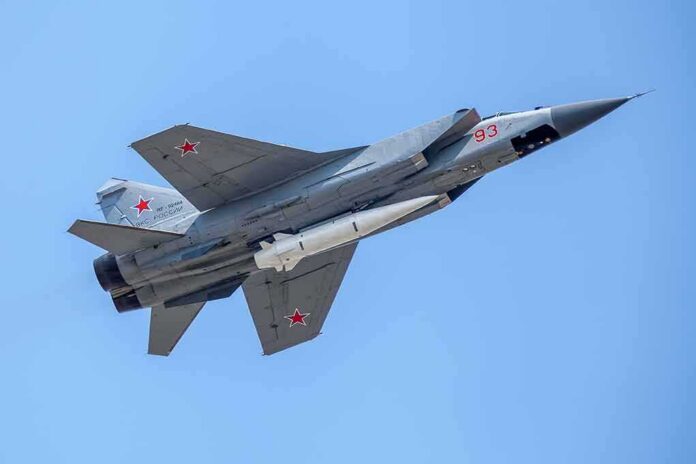 fighter jet with missile flying against a clear blue sky