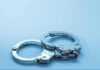 Metal handcuffs on a light blue surface