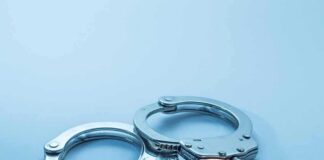 Metal handcuffs on a light blue surface