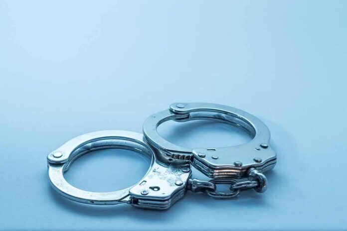 Metal handcuffs on a light blue surface