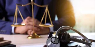 Gavel with stethoscope on desk near scales of justice