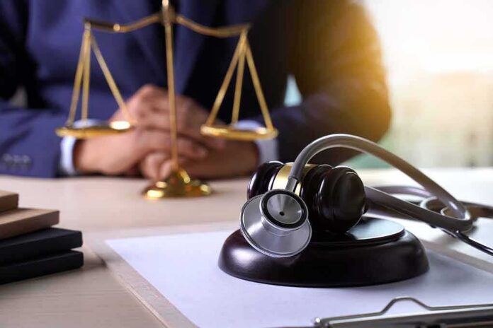 shutterstock_1135682939 Gavel with stethoscope on desk near scales of justice