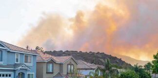 Suburban street with wildfire smoke over nearby hills
