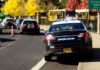 Police cars with lights on near school buses on a city street