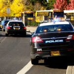 Hoax Panic Slams Louisiana Classrooms Police cars with lights on near school buses on a city street
