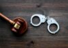 Hate Rampage Shocks LA Transit Judge's gavel and metal handcuffs on wooden table