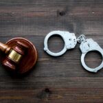 Hate Rampage Shocks LA Transit Judge's gavel and metal handcuffs on wooden table